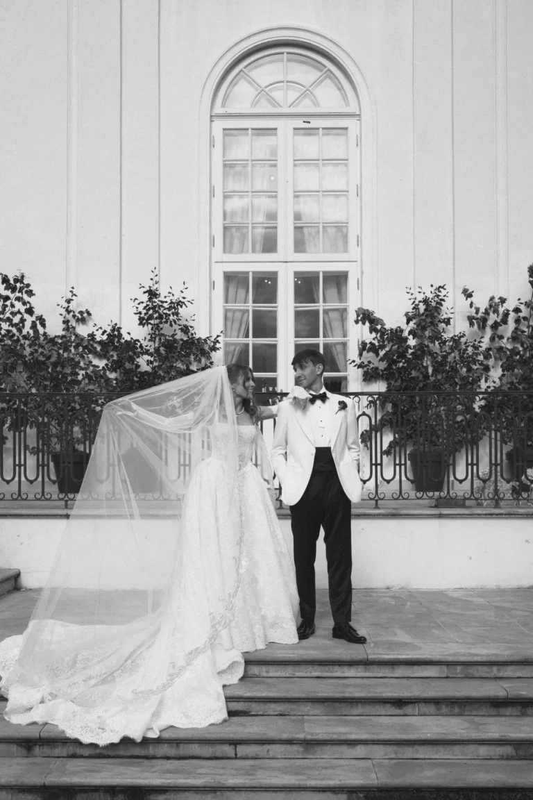 Bride and groom on the palace steps, long veil spread across the stairs