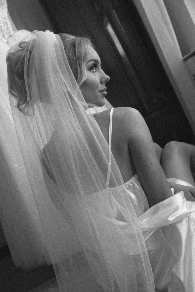 Bride in a veil glancing over her shoulder by the window
