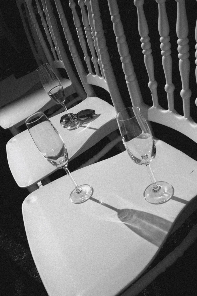 Champagne flutes and sunglasses on white chairs