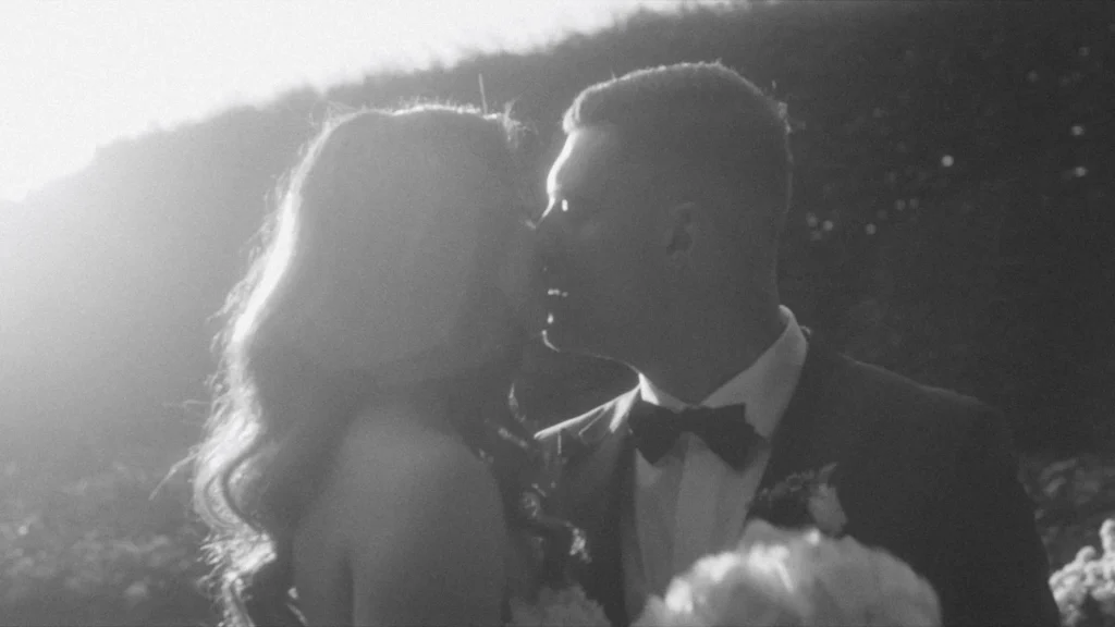 Backlit kiss on the cheek against a sunlit hedge