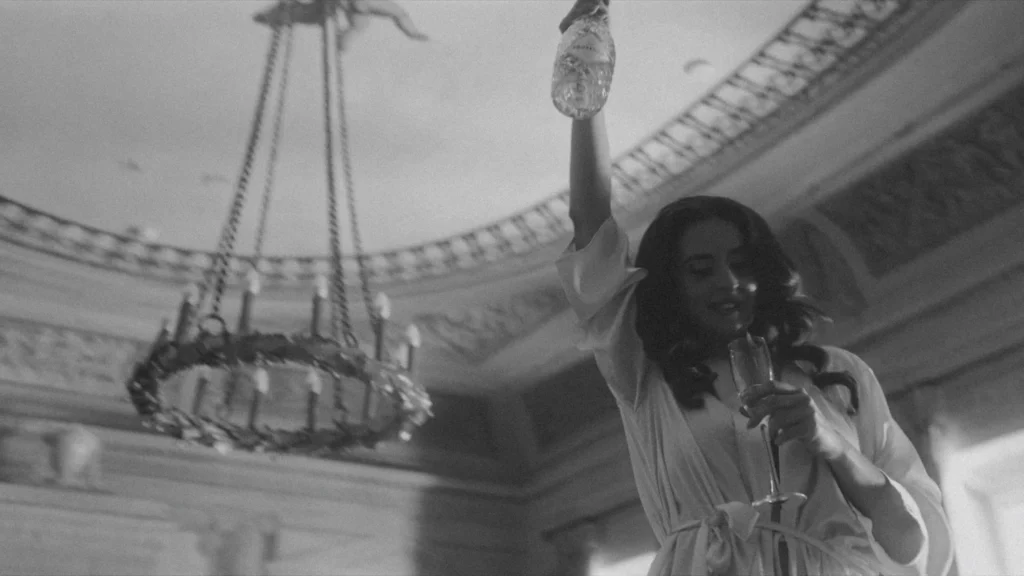 Bride raising a champagne bottle beneath a chandelier in a domed hall