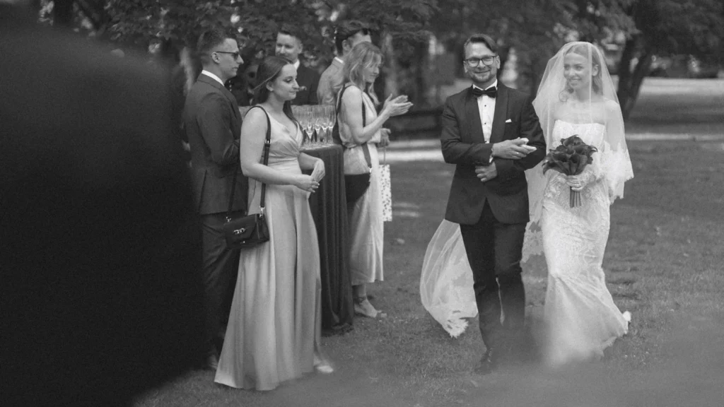 Bride's entrance past guests on the lawn, in black and white