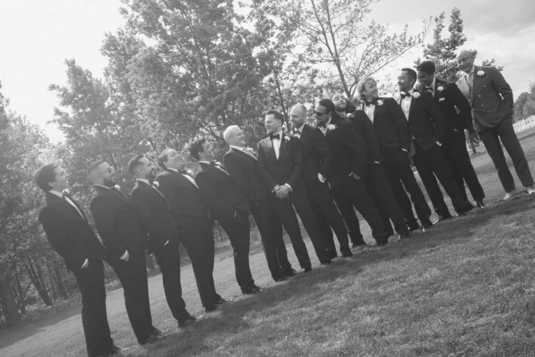 Groom and his groomsmen lined up in tuxedos, laughing